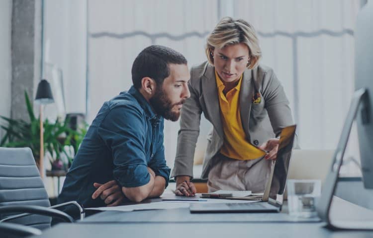 Man And Woman Looking Over Laptop